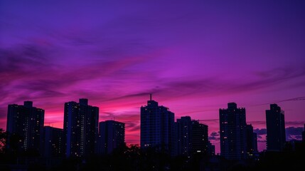 Fototapeta premium Twilight Cityscape: Silhouette of Urban Landscape Against Vibrant Purple Sky