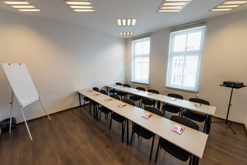 Conference room with benches, tables and a projector. Empty Conference Room In Modern Office. Interior of a classroom with white walls and wooden floor.  Office Business.