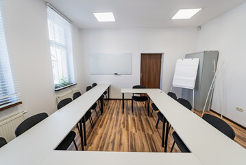 Conference room with benches, tables and a projector. Empty Conference Room In Modern Office. Interior of a classroom with white walls and wooden floor.  Office Business.