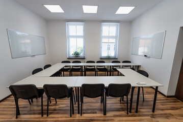 Conference room with benches, tables and a projector. Empty Conference Room In Modern Office. Interior of a classroom with white walls and wooden floor.  Office Business.