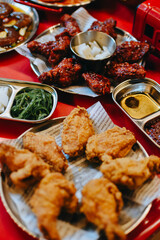 Traditional Korean Fried chicken and fried chicken with spicy,  sweet sauce with seaweed, radish pickled on red table. Traditional Korean street food.