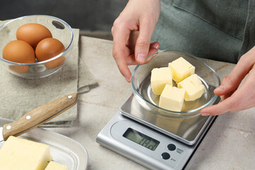 Woman weighing butter on kitchen scale at grey table, closeup