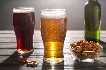 Glasses of beer and pretzel crackers on grey wooden table