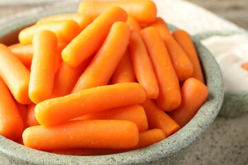 Baby carrots in bowl on table, closeup