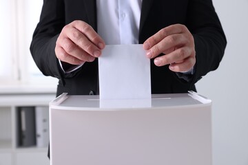 Man putting his vote into ballot box indoors, closeup