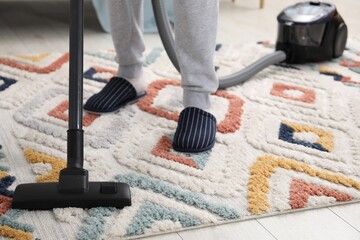 Man with vacuum cleaning carpet indoors, closeup