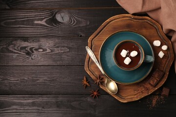 Tasty melted chocolate with marshmallows in cup and anise stars on dark wooden table, flat lay. Space for text