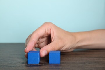 Woman with blue cubes at wooden table, closeup