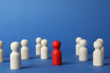 Red piece among wooden ones on blue background