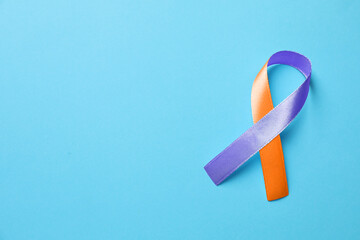 World Psoriasis Day. Orange and orchid awareness ribbon as symbol of support on light blue background, top view. Space for text