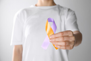 World Psoriasis Day. Woman with orange and orchid ribbon as symbol of support on white background, closeup