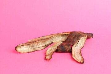 Banana peel with dark spots on pink background