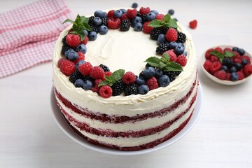 Tasty sponge cake with different berries and mint on white wooden table