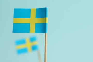 Obraz premium Small paper flags of Sweden on light blue background, selective focus. Space for text
