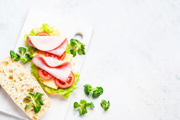 Sandwich with lettuce, cheese, tomatoes and ham. Healthy fast food or snack. Top view on white.
