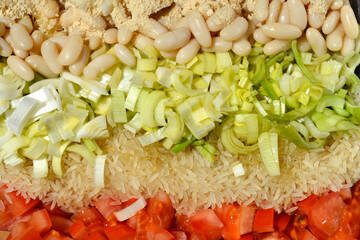 Preparing vegan meal made of tomatos, rice, leek, white beans and nutritional yeast