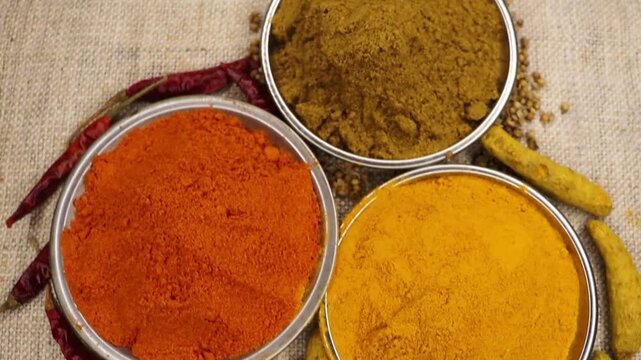 Close up 4k shot of turmeric, red chili, cumin and coriander powder in bowl, top view. Main 3 spices for Indian Africa Morocco Asian cuisine. Colorful spices.