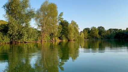 Serene Lake with Reflective Calm Waters and Verdant Forest Landscape on a Sunny Day