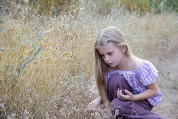 Curious little girl exploring plants on the meadow