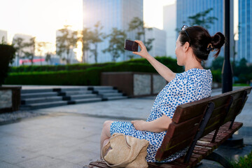 Young woman taking selfie with mobile phone on park bench