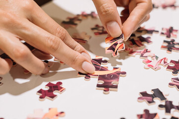 Hands of an unrecognizable person putting together pieces of a puzzle