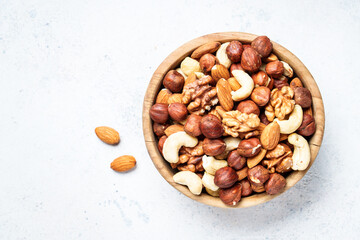Nuts assortment at white background. Almond, hazelnut, cashew in wooden bowl. Flat lay.