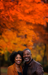 Fototapeta premium portrait of middle age african american couple standing outside; autumn/fall forest as a background; copy space for text