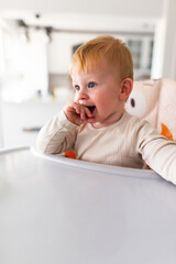 an emotional toddler sitting in a highchair.leery eye