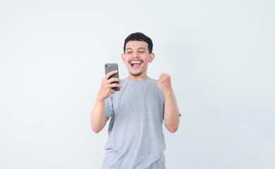 A man clenched fist and showing amazed facial expression when looking to handphone that he hold