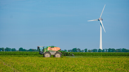 Tractor spraying pesticides on crops, farmer spring the land in the Netherlands