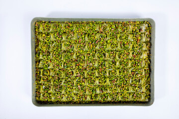Top view of traditional Gaziantep cimcik baklava on a tray isolated on white background.