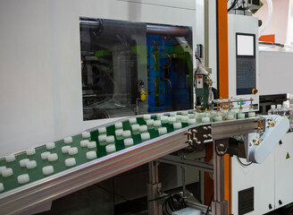 Plastic bottle caps on conveyor belt from plastic injection molding press machine. Industrial...
