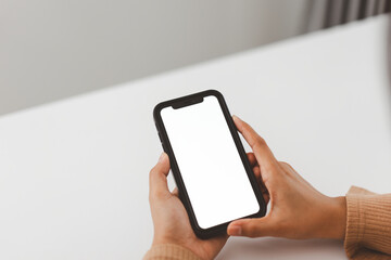 Hands holding smartphone with blank white screen, ready for customization, on a plain white background.