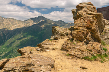 The rocks are located high in the mountains. The nature of the highlands. A landscape with views of cliffs and snow-capped peaks.
