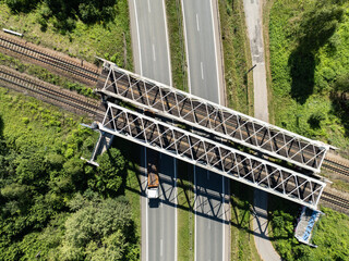 Fototapeta premium Aerial view from the drone of the railway bridge over the expressway. Freight train on metal iron bridge. Tracks and an iron railway bridge against the background of green fields.
