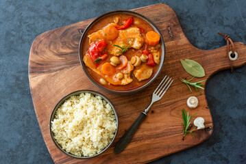Fried pork loin in tomato sauce with mushrooms, red peppers and carrots served with couscous