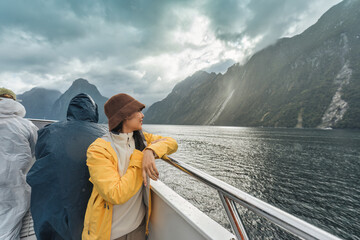 Asian woman enjoying the view of Milford Sound during ferry cruise on vacation at New Zealand