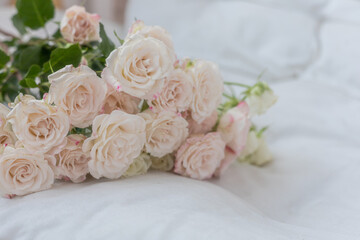 A bouquet of beautiful white rose flowers on the bed or sofa indoors closeup. Romance, Honeymoon, birthday, love concept.