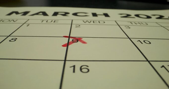 A person crosses out a number in the schedule table with a red marker. Close-up of the marker, an unrecognizable person