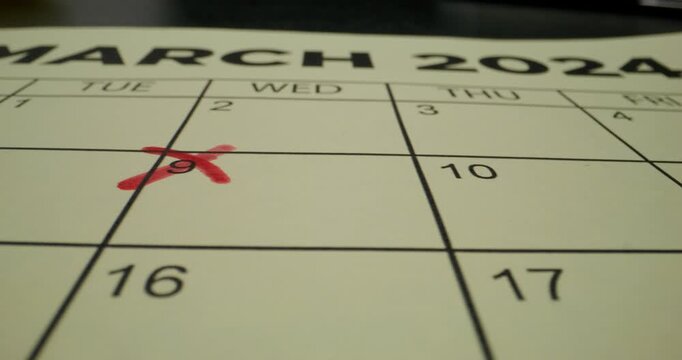 A schedule table with days of the week and numbers. One of the dates is crossed out with a red cross. Close-up