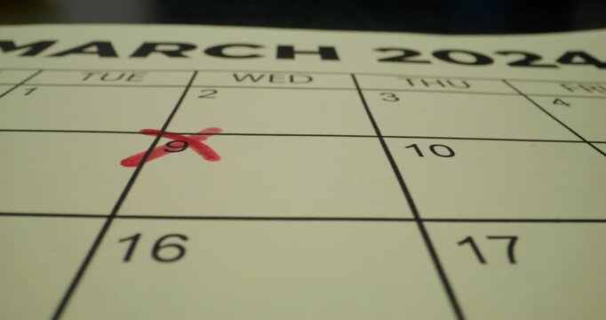 A schedule table with days of the week and numbers. One of the dates is crossed out with a red cross. Close-up