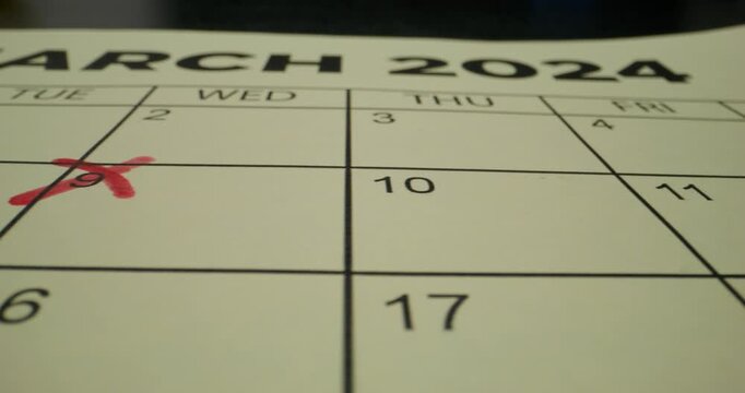 A schedule table with days of the week and numbers. One of the dates is crossed out with a red cross. Close-up