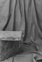 podium made of grey stone on a grey fabric background