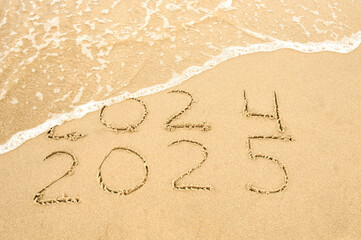 Inscription 2024 and 2025 numbers written on sand.  New Year 2025 replace 2024. Concept on the sea beach
