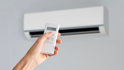 Hand holding remote controller directed on the air conditioner