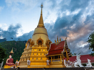 Fototapeta premium Wat Phra That Doi Chiang Dao. Chedi in Chiang Dao and monk statue of Great Master Narasabho Mahathera at sunset.