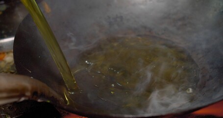 Close-up view of oil being poured into a hot wok with smoking ready for cooking, Close-Up View of...