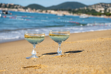 Summer time on French Riviera, two coupe glasses of champagne cremant sparkling wine on Pampelonne sandy beach near Saint-Tropez in sunny day, Var, vacation in France