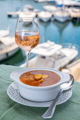 Homemade tasty fish or bisque soup with croutons served with glass of cold rose wine and view on...