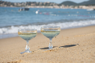 Summer time on French Riviera, two coupe glasses of champagne cremant sparkling wine on Pampelonne sandy beach near Saint-Tropez in sunny day, Var, vacation in France